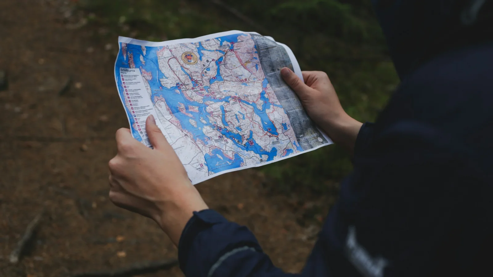 Person mit gefalteter Landkarte in einem Wald – Sinnbild für ein vorbereitetes intensivpädagogisches Reiseprojekt